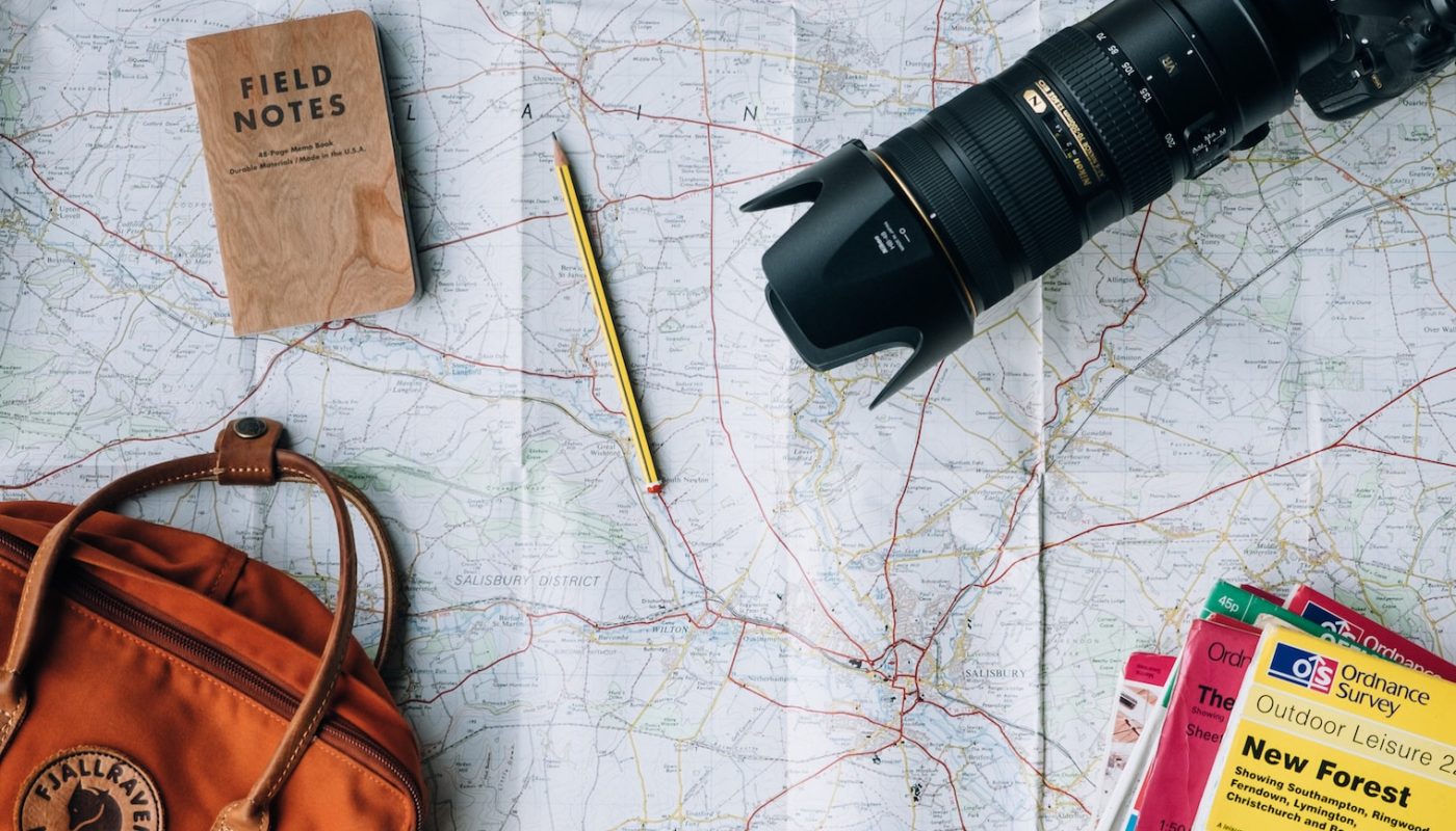 flat lay photography of camera, book, and bag