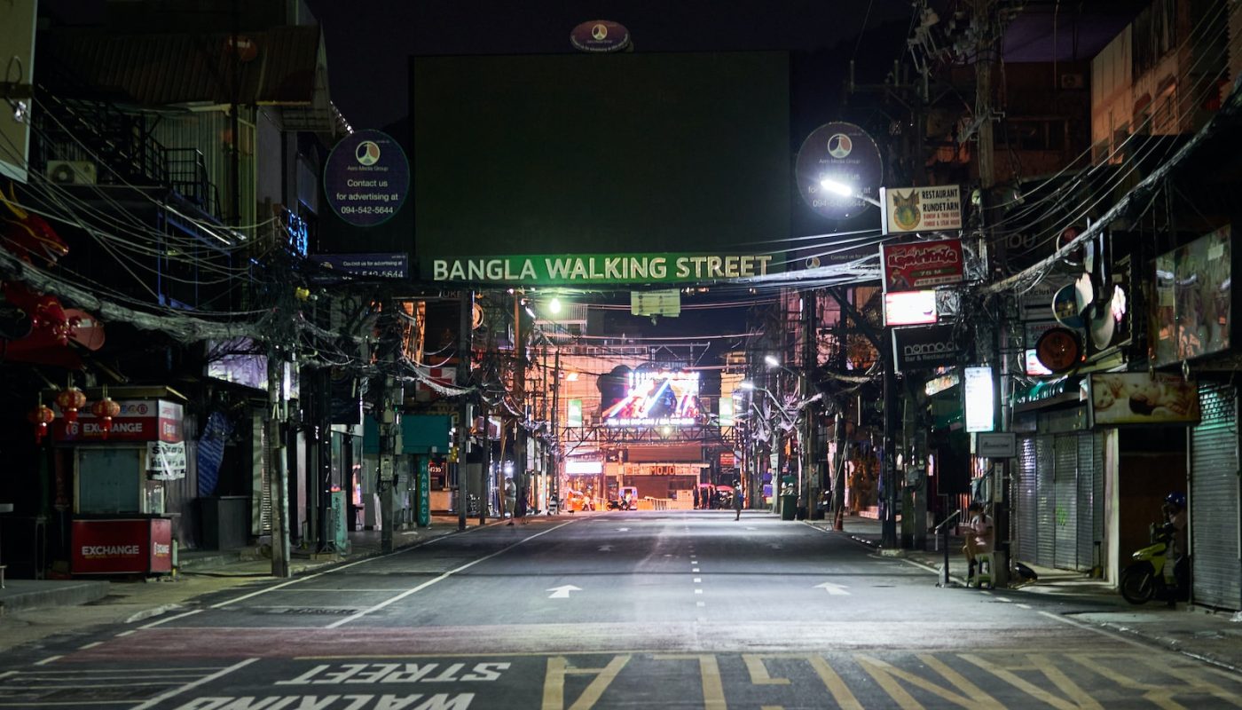 an empty street at night with a neon sign
